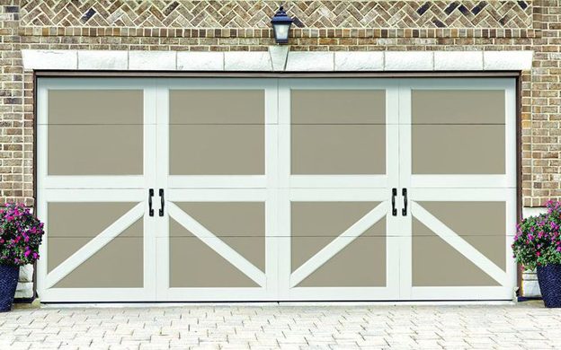 A tan and white Amarr Carriage Court garage door with crossbucks and black handles on a brick garage
