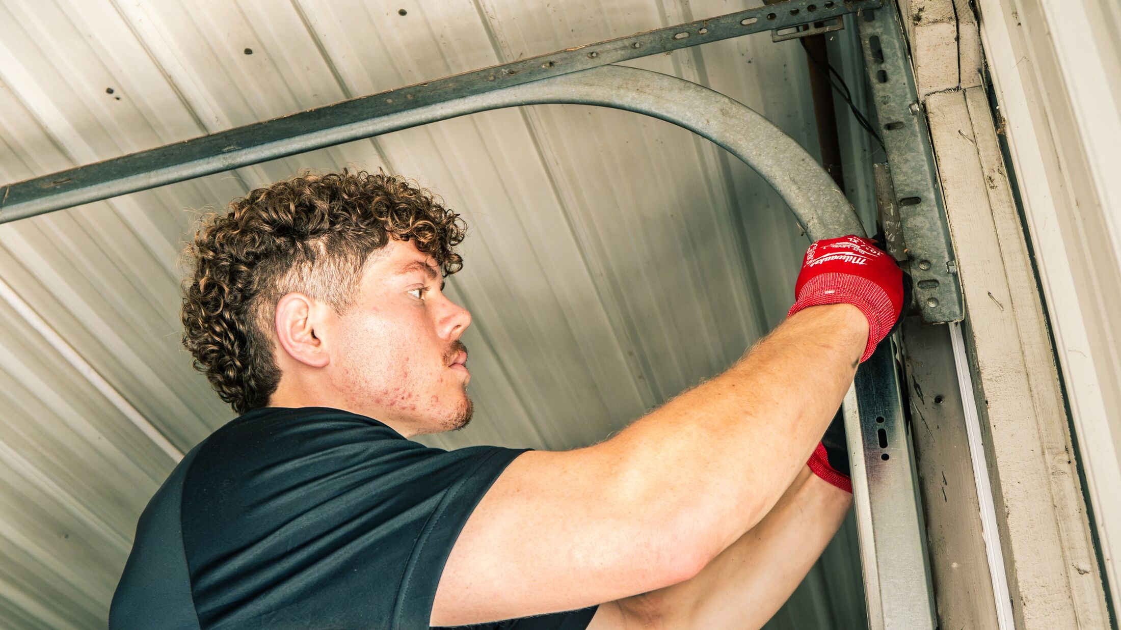 An Elevation technician working the curved track at the top of a garage door opening