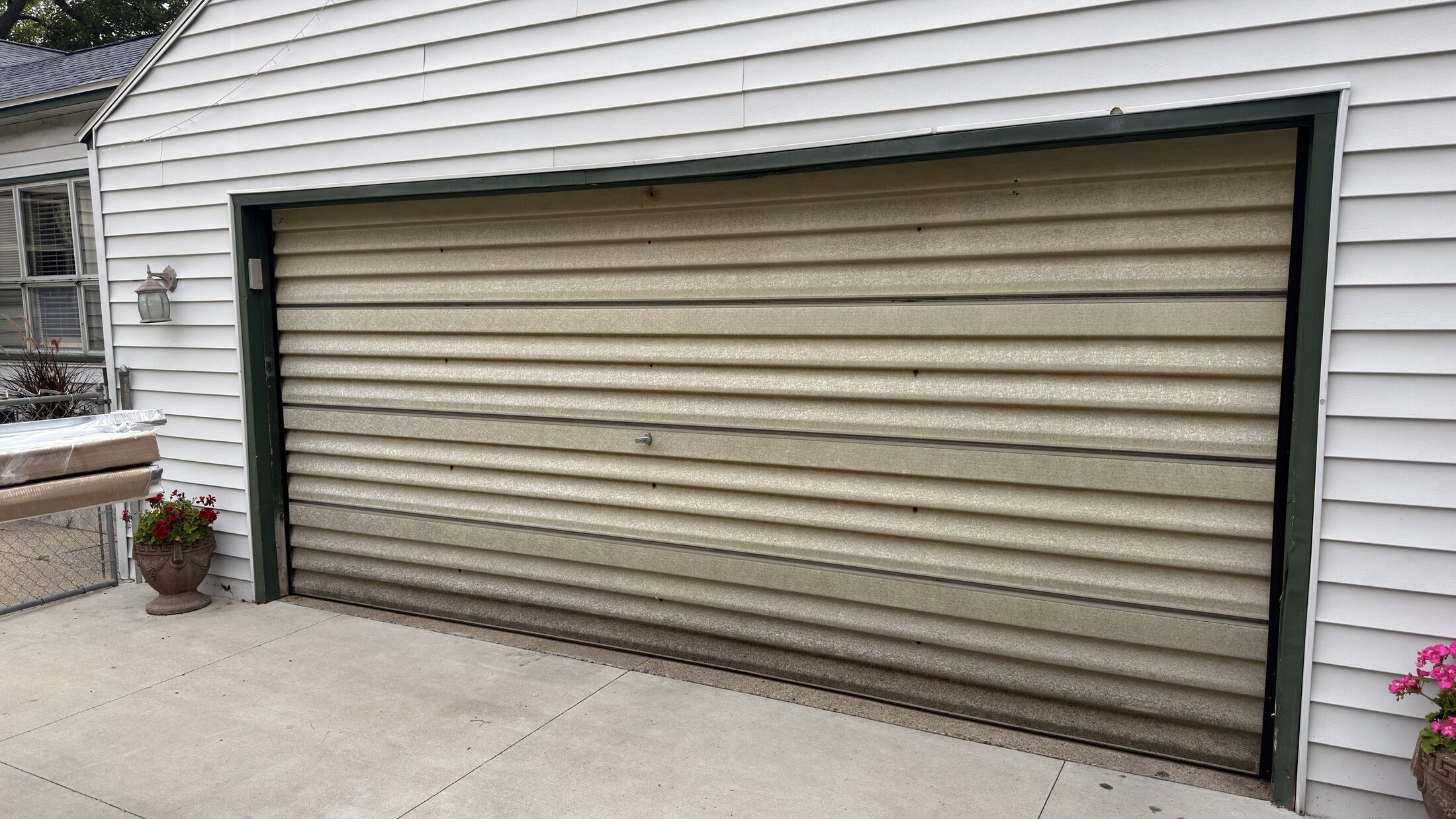A faded, streaked brown garage door on a grey-sided garage in Wyoming