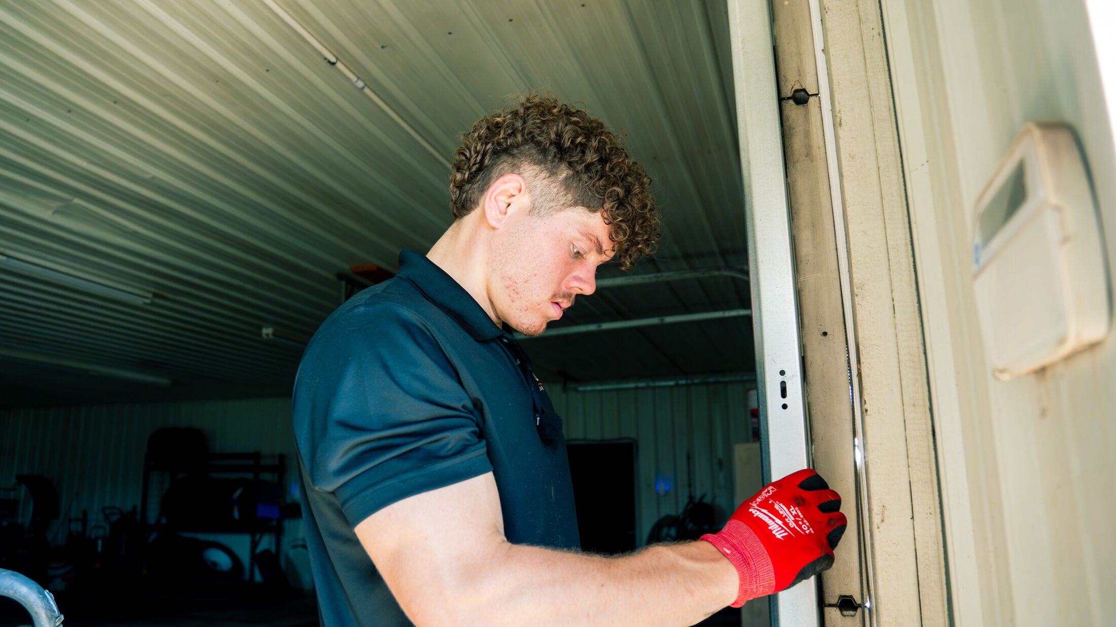 An Elevation technician checking the lock and jamb hardware on a garage door during a fall tune-up