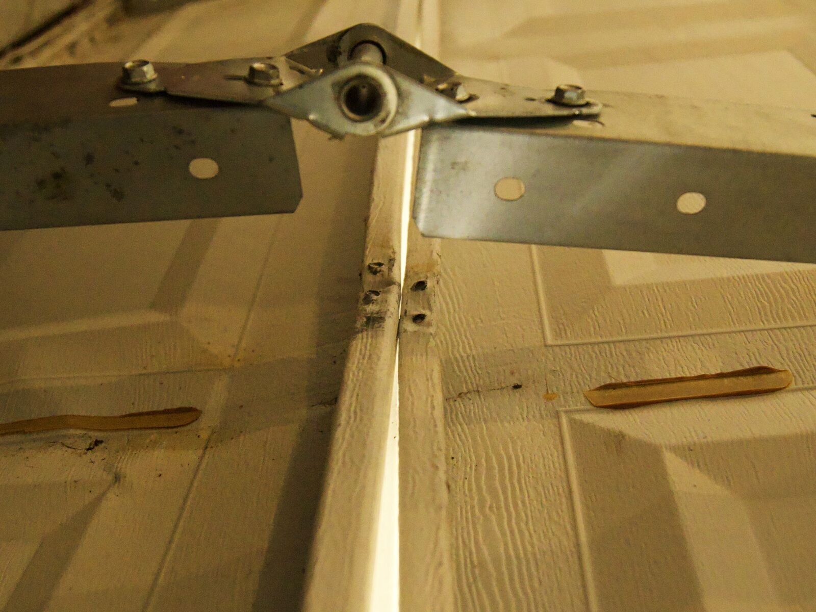 A reinforcement strut and hinge on a garage door, checked and lubricated during a tune-up