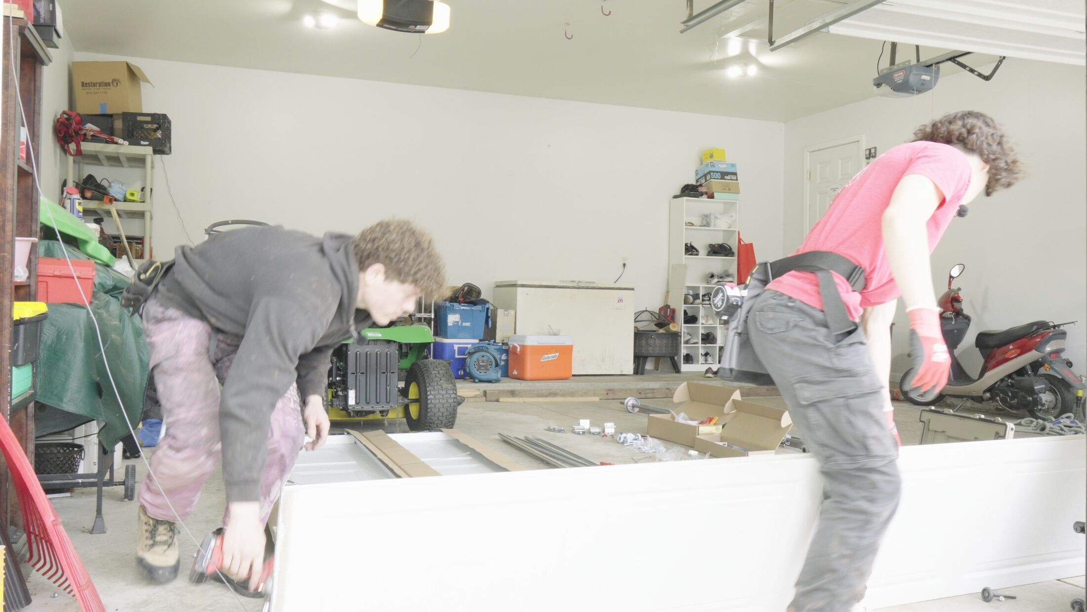 Two Elevation technicians setting a new garage door section on the floor during an install