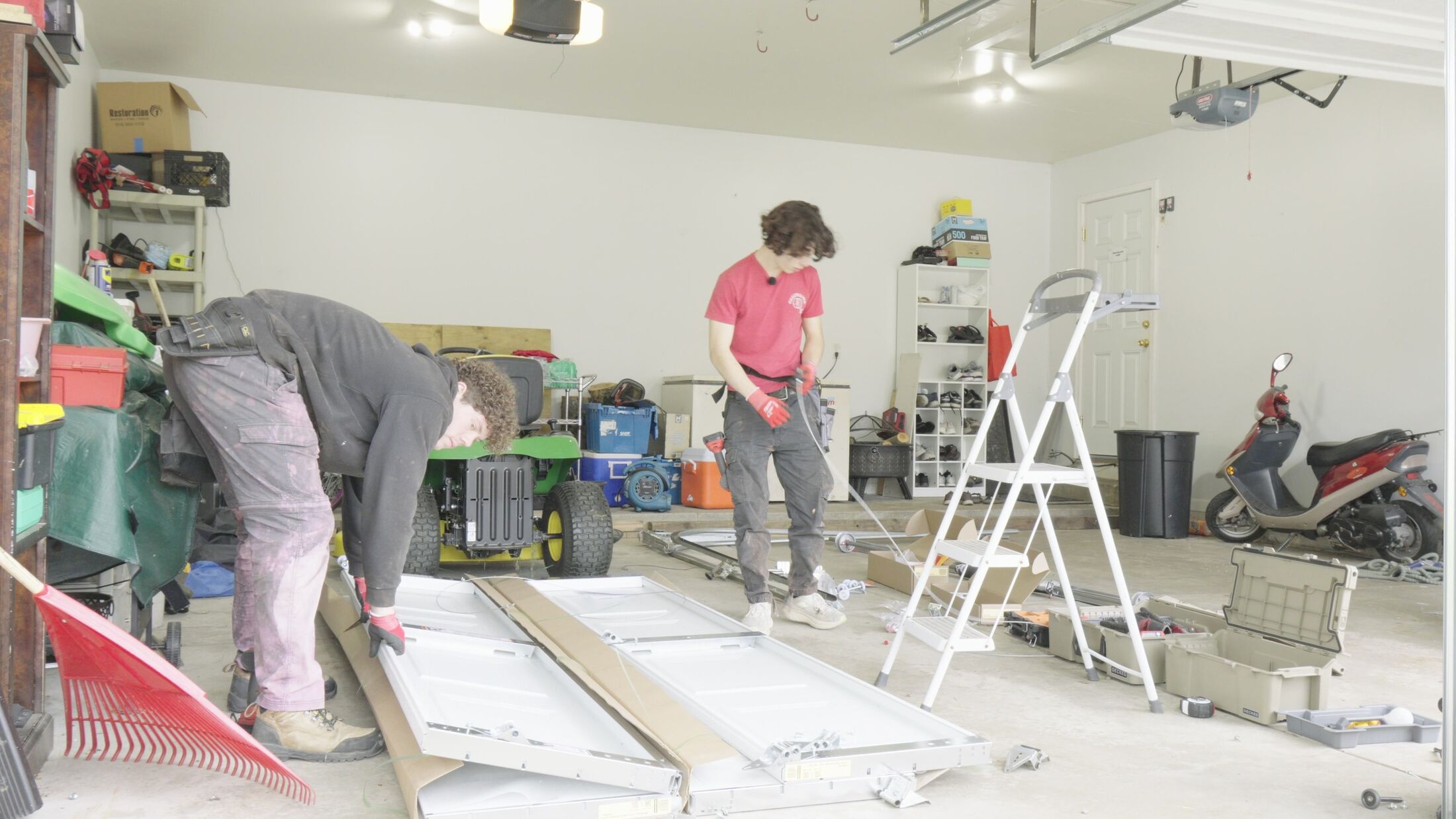 Elevation technicians laying out track and door sections on a garage floor during an installation