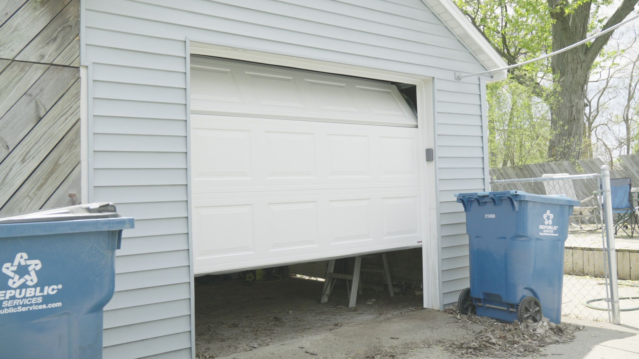 The newly installed garage door part way open, showing the fresh track and the garage behind it