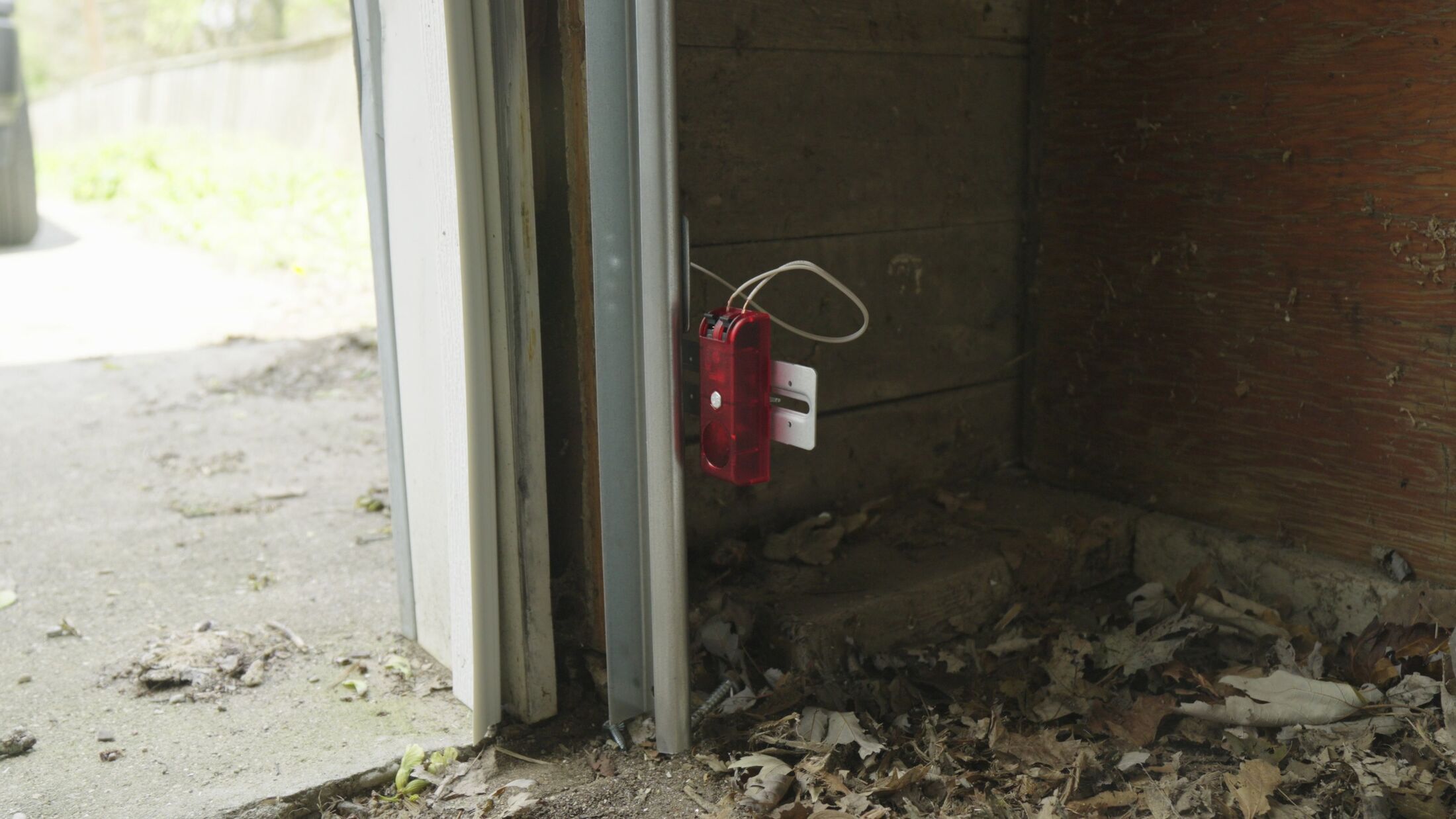 A photo-eye safety sensor at the base of a garage door jamb, being aligned