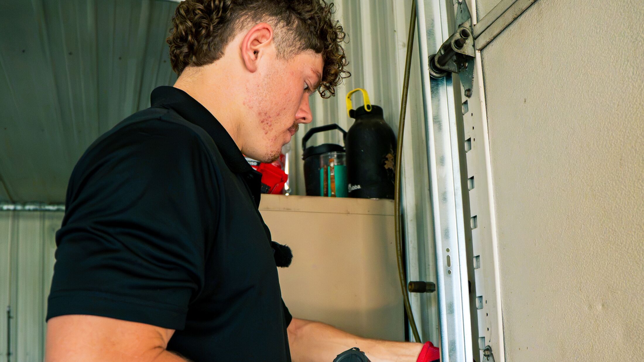 An Elevation technician working on a customer's overhead garage door with a cordless impact driver