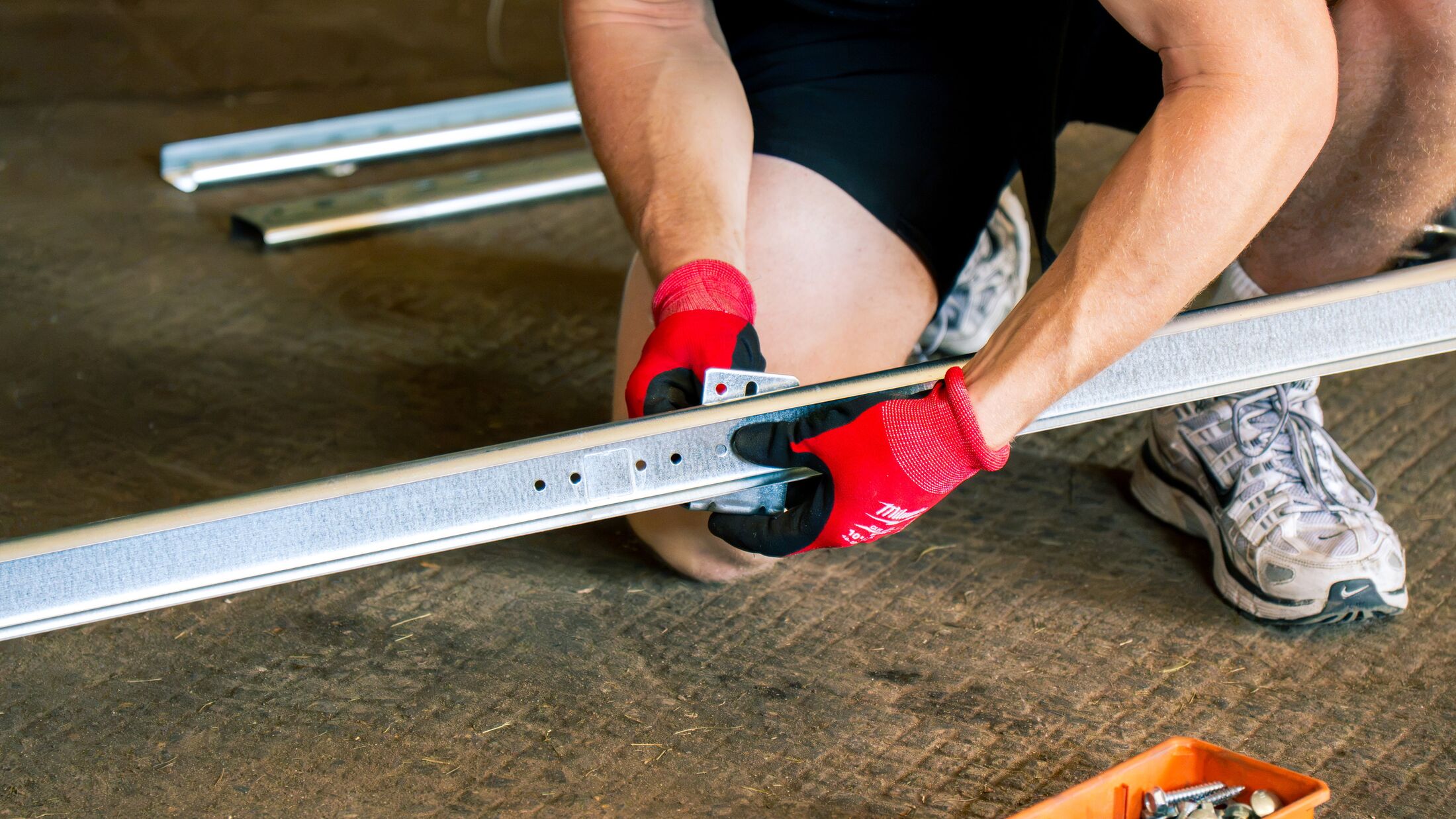 Close-up of a new garage door track rail held in a technician's gloved hands